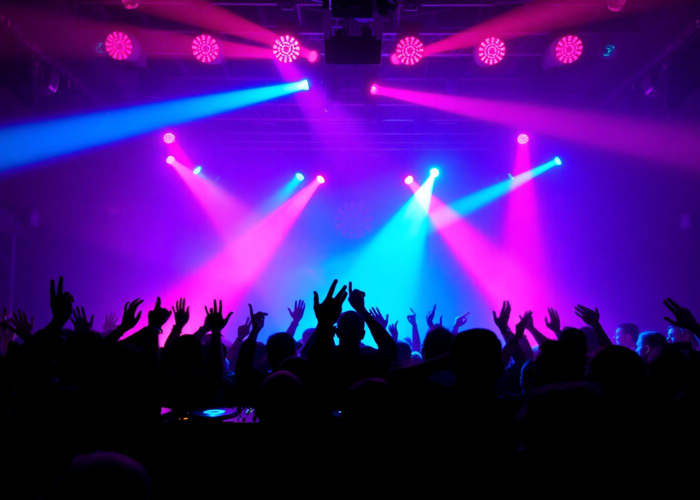 DJ set with crowd raising hands under stage lights